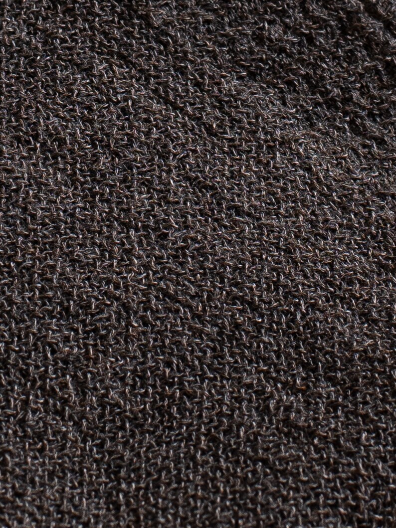 May include: Close-up of a dark brown knitted fabric with a textured surface.