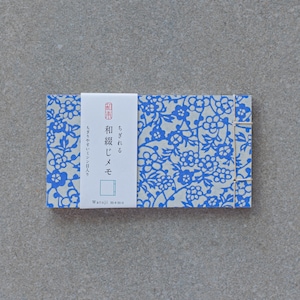 May include: A small, white notebook with a blue floral pattern and a white label that says "Watoji memo" and has Japanese text that reads "和紙メモ" which translates to "Japanese paper memo".