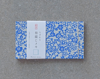May include: A small, white notebook with a blue floral pattern and a white label that says "Watoji memo" and has Japanese text that reads "和紙メモ" which translates to "Japanese paper memo".