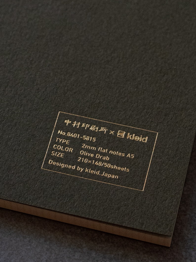 May include: A black notebook with gold lettering that reads "中村印刷所&times;kleid No.8401-5815 TYPE 2mm flat notes A5 COLOR Olive Drab SIZE 210x148/50sheets Designed by kleid. Japan"