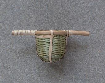 May include: A woven bamboo tea infuser with a handle. The infuser is light brown and has a natural woven pattern.