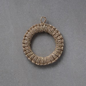 May include: A round, woven pot holder made of natural fibres. The holder has a loop at the top for hanging.