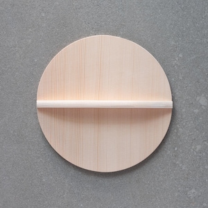 Puede incluir: Estante redondo de madera clara con una barra horizontal. El estante es de madera clara con veta natural. Se monta sobre una superficie gris.