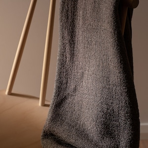 May include: A brown throw blanket draped over a wooden chair. The chair has a light wood finish and a simple design.