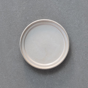 Może przedstawiać: Okrągły, kremowy ceramiczny talerz z lekko podniesionym brzegiem. Talerz ma prosty, minimalistyczny design, idealny do serwowania potraw. Talerz jest ustawiony na szarym tle.