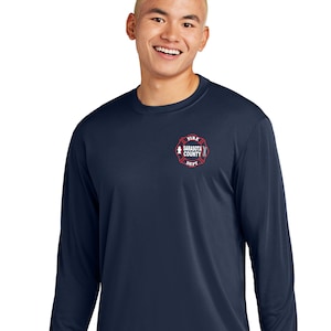 Puede incluir: Una camisa de manga larga azul marino con un logotipo bordado en rojo y blanco que dice "Fire Sarasota County Dept."