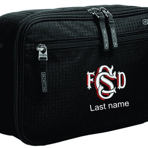 Puede incluir: Bolsa de viaje negra con cierre de cremallera y un diseño de monograma. El monograma es en rojo y blanco con las iniciales "FSD" y el texto "Last name".