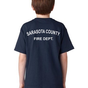 Puede incluir: Una camiseta azul marino para jóvenes con texto blanco que dice "Sarasota County Fire Dept."