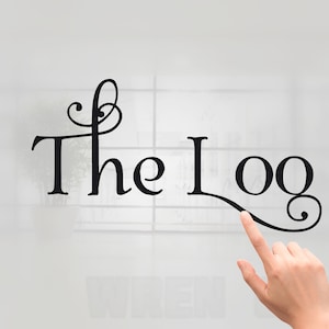 May include: Black cursive text that reads "The Log" with a decorative flourish. A hand is pointing at the word "Log". The background is a blurred white and gray.