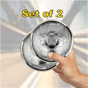 May include: Set of two clear glass headlights with chrome bezels. The headlights are held in a hand.