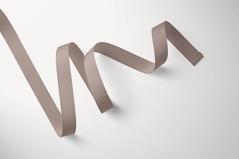 May include: A length of light brown satin ribbon is curled and twisted on a white background.