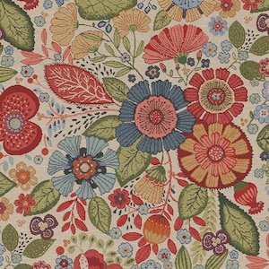 Op de afbeelding: Een kleurrijke stoffen stof met een bloemenpatroon met verschillende bloemen, bladeren en stengels in tinten rood, blauw, geel en groen op een crèmekleurige achtergrond.