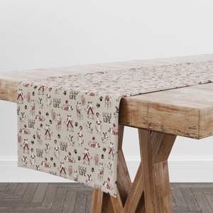 Peut inclure: Un chemin de table beige avec un motif répété de chiens de dessin animé jouant avec des balles, des os et une niche. Le texte "Dogs Life" est répété sur tout le motif.