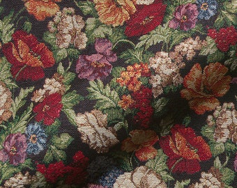 May include: A close-up of a black fabric with a floral pattern. The fabric features a variety of flowers in shades of red, pink, yellow, and white. The flowers are arranged in a random pattern and are surrounded by green leaves.