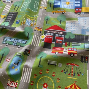 May include: A colourful play mat with a city theme. The mat features a variety of buildings, vehicles, and street signs. There is a park with a pond, a playground with a Ferris wheel and a carousel, and a fire station with a fire engine. The mat is made of a soft, durable fabric and is perfect for children to play on.
