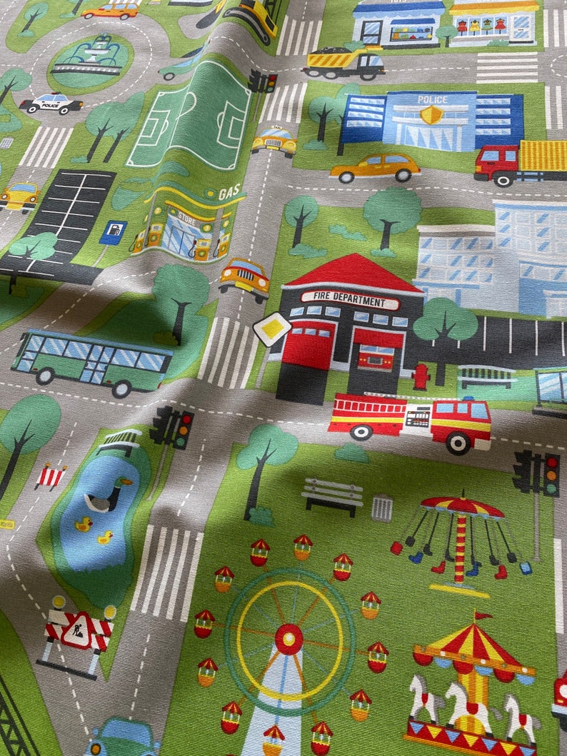 May include: A colourful play mat with a city theme. The mat features a variety of buildings, vehicles, and street signs. There is a park with a pond, a playground with a Ferris wheel and a carousel, and a fire station with a fire engine. The mat is made of a soft, durable fabric and is perfect for children to play on.