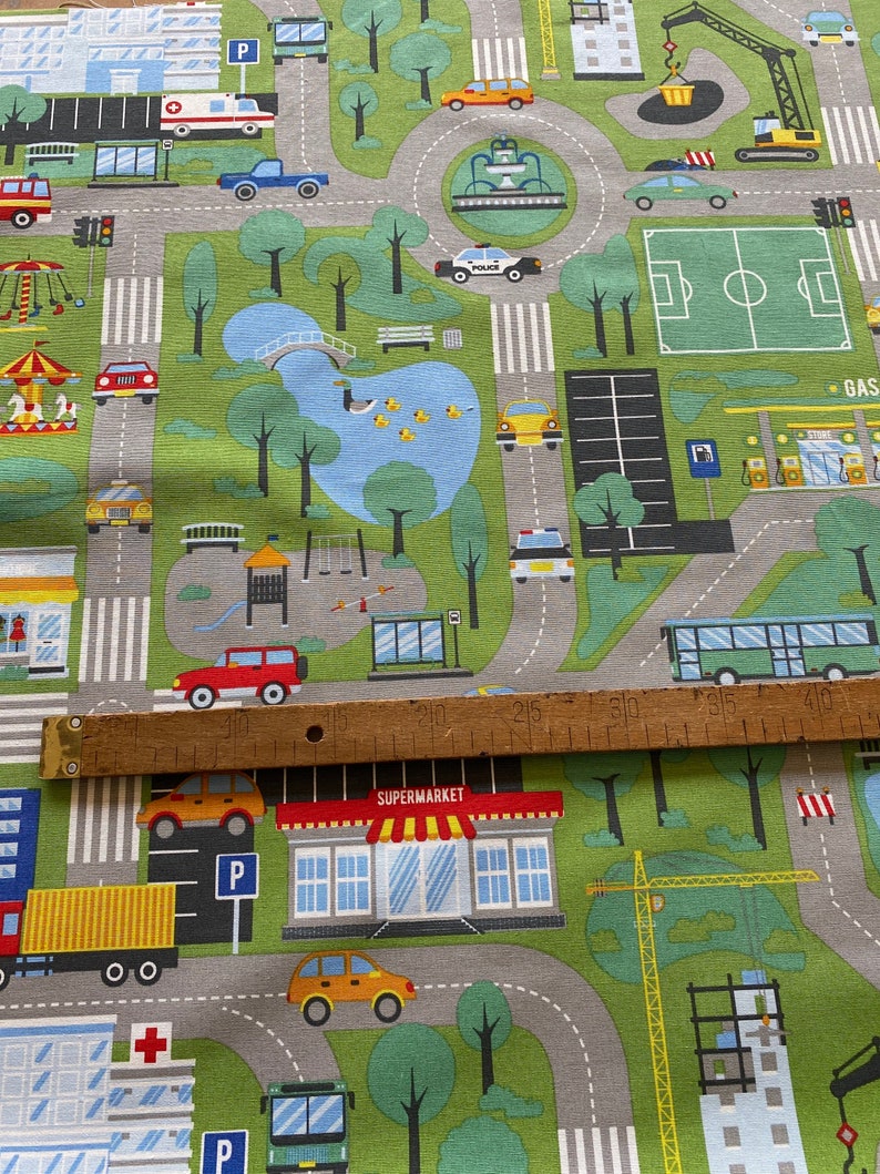 May include: A colourful play mat with a city theme. The mat features roads, buildings, cars, a park, a football pitch, a petrol station, and a supermarket. The mat is made of a soft, durable material and is perfect for children to play on.