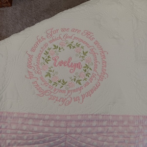 May include: White baby blanket with pink embroidered roses and the text "For we are His work, created in Christ Jesus, for good works, which God prepared beforehand that we should walk in them. Ephesians 2:10" and the name "Evelyn" in a circle.