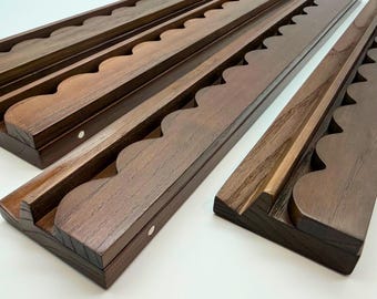 Puede incluir: Cuatro expositores largos de madera de color marrón oscuro dispuestos en diagonal. Cada expositor presenta una serie de recortes festoneados redondeados y uniformes a lo largo de un borde, creando un perfil ondulado. Se aprecia la veta.