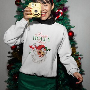 May include: White Christmas sweatshirt with a vintage Santa Claus illustration and the text "Happy Holly Days".