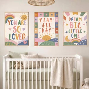 Könnte beinhalten: Drei rechteckige Wandbilder mit farbenfrohen Illustrationen und Text. Das linke Bild zeigt YOU ARE SO LOVED mit Regenbogen und Sonne. Das mittlere Bild zeigt PLAY ALL DAY mit Sonne und kariertem Rand. Das rechte Bild zeigt DREAM BIG LITTLE ONE mit Mond und Regenbogen.