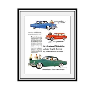 May include: A framed vintage advertisement for 1954 Studebaker automobiles featuring a blue sedan, a red station wagon, and a green coupe. The text includes Get ahead of the parade, Get more when you trade, and Studebaker is first in America.