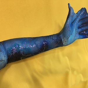 May include: A long blue glove with a snakeskin pattern. The glove has a long finger and a thumb, and the rest of the fingers are connected.