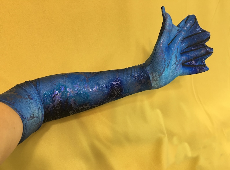 May include: A long blue glove with a snakeskin pattern. The glove has a long finger and a thumb, and the rest of the fingers are connected.