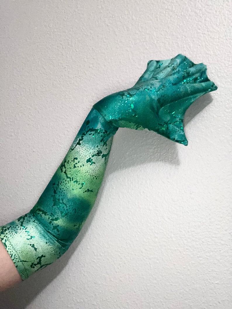 May include: A long, green and white arm sleeve with a glittery finish. The sleeve has a snake skin pattern and is made of a stretchy fabric.
