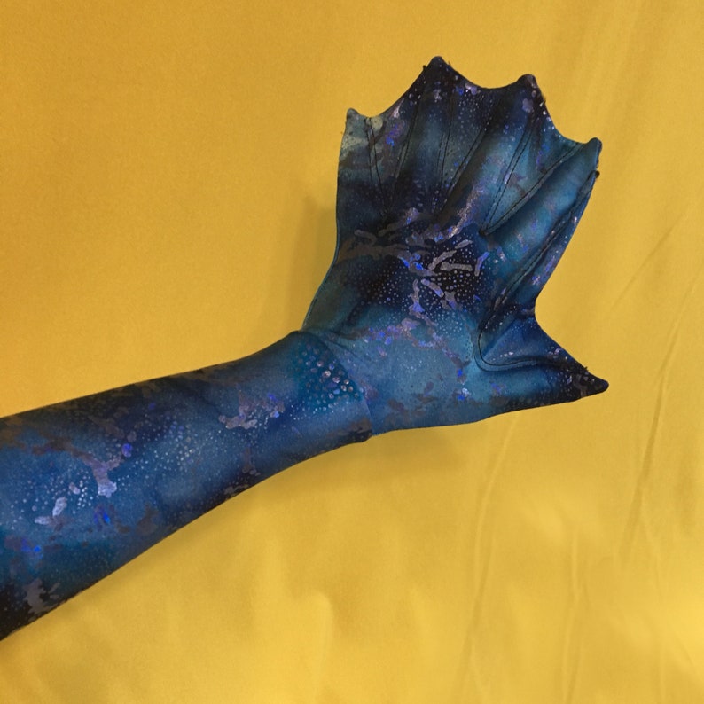 May include: A blue and purple mermaid fin glove with a textured surface. The glove is made of a stretchy fabric and has a pointed tip.