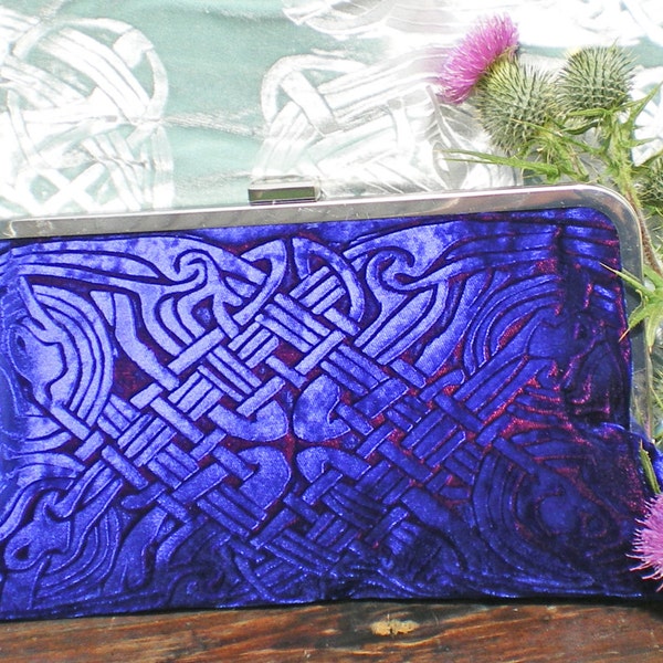 A strong blue kisslock clutch bag in an embossed iridescent velvet celtic design