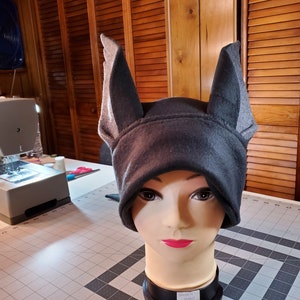 May include: A gray fleece hat with two large, pointed ears. The hat is on a mannequin head.
