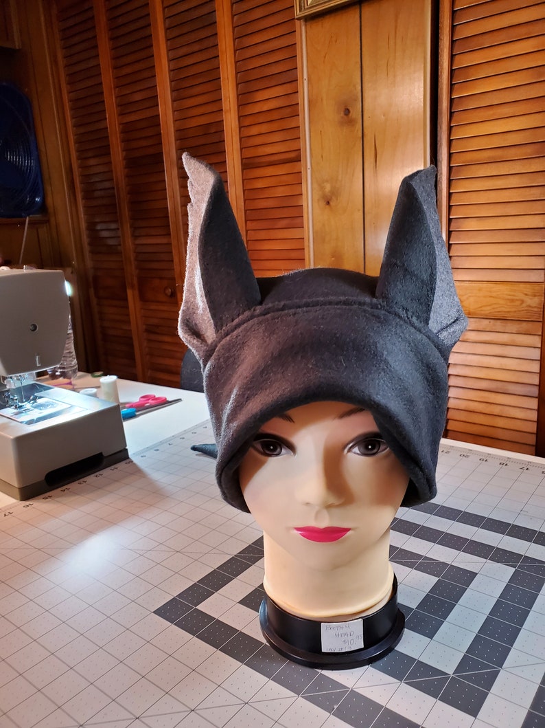May include: A gray fleece hat with two large, pointed ears. The hat is on a mannequin head.