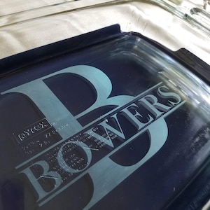 May include: A blue glass baking dish with a white design that says "Bowers" with a large "B" in the front. The dish is made by Pyrex and has a 22.6 cm (9 inch) diameter.