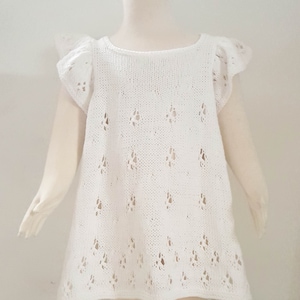 May include: White crocheted dress with a delicate floral pattern and short, ruffled sleeves.