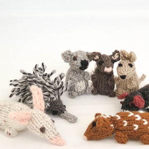 Puede incluir: Una colección de juguetes de animales de punto, que incluyen un koala, un bandicoot, un equidna, un wombat, un quoll y un lagarto. Los juguetes están hechos con hilo de diferentes colores y tienen características realistas.