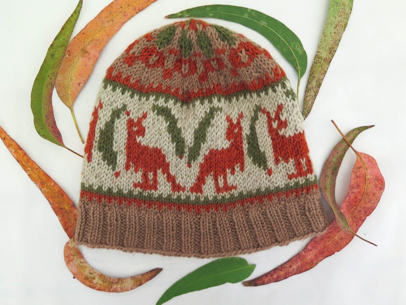 May include: A brown knitted hat with a white, orange, and green pattern of kangaroos. The hat has a fold-over brim.