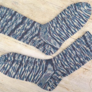 May include: A pair of blue, white, and purple striped socks. The socks are made of a soft, knitted fabric.