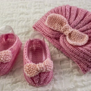 Puede incluir: Un conjunto de botines de bebé de punto rosa y un gorro a juego con un lazo. Los botines y el gorro están hechos con un hilo suave y delicado.