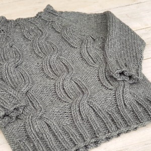 May include: A gray knitted sweater with a cable knit pattern.