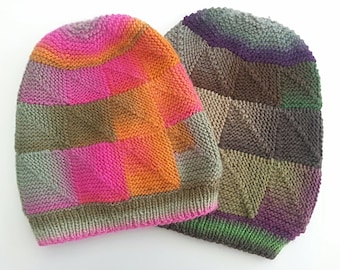 Puede incluir: Dos gorros de punto con un patrón de cuadros. Un gorro es rosa, naranja y verde, y el otro es marrón, verde y morado.