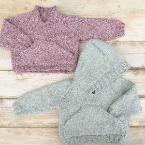 May include: Two knitted sweaters, one in a pink and white speckled pattern and the other in a green and white speckled pattern. The pink sweater has a turtleneck and the green sweater has a hood.