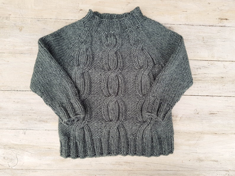 May include: A dark gray cable knit sweater with a high neck.