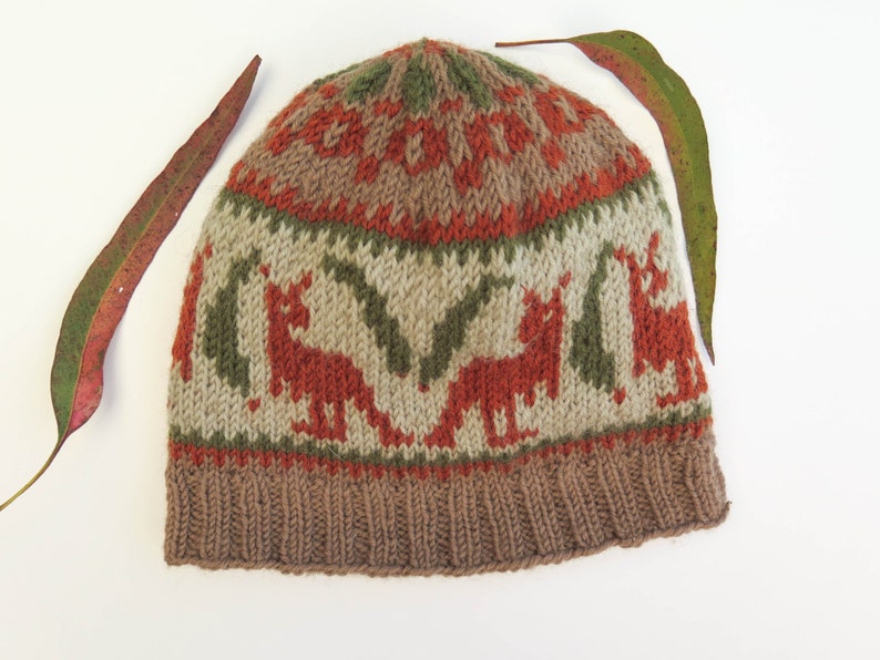 May include: A brown, green, and orange knitted hat with a pattern of stylized animals. The hat has a fold-over cuff.