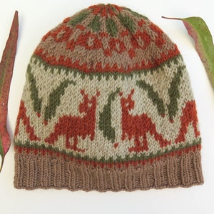 May include: A brown, green, and orange knitted hat with a pattern of stylized animals. The hat has a fold-over brim.