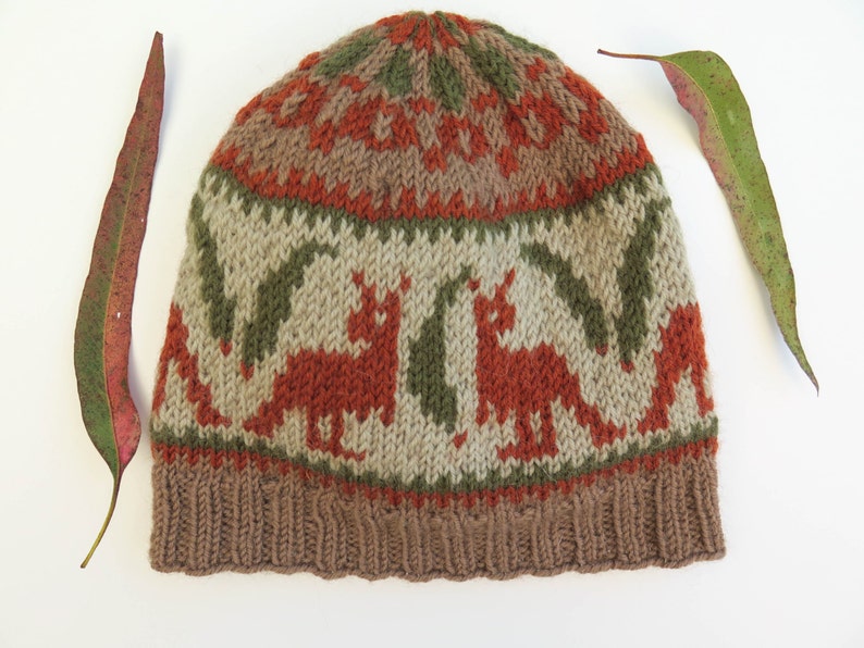 May include: A brown, green, and orange knitted hat with a pattern of stylized animals. The hat has a fold-over brim.
