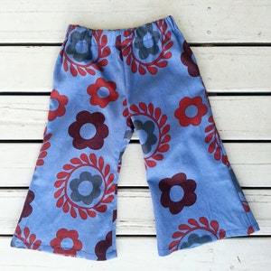 Puede incluir: Pantalones acampanados azules con un estampado floral rojo y azul oscuro.