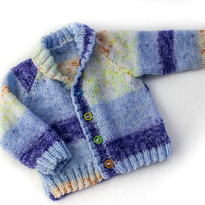May include: A blue and purple striped knitted cardigan with a button closure. The cardigan has a light blue and white speckled pattern.