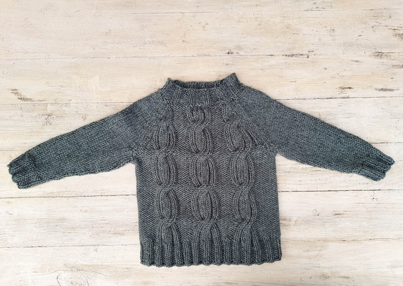 May include: A gray knitted sweater with a cable knit pattern.