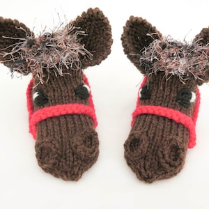 May include: A pair of brown knitted horse head slippers with red bridles and fuzzy brown manes.